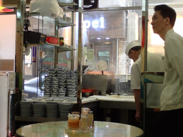 Hong Kong – Mac’s noodles à Wellington street. Mac’s est célèbre pour sa “Wanton noodle soup”, soupe de ravioli servie en petites portions et pour ses serveurs en livrée. Le bouillon non bu est reversé dans la marmite. Les amateurs dégustent leur soupe plutôt en fin d’après-midi, les bouillons reversés ont eu le temps de se faire culture. 